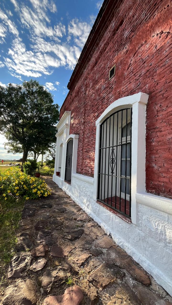 Fachada de ladrillo con ventanas de rejas y camino de piedra